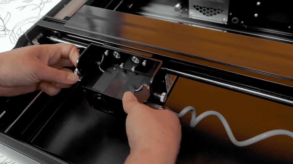 Hands lifting the honeycomb panel out of the WeCreat Vista to make room for the rotary attachment