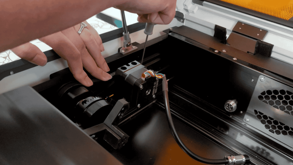Hands connecting the rotary attachment cable inside the WeCreat Vista laser engraver