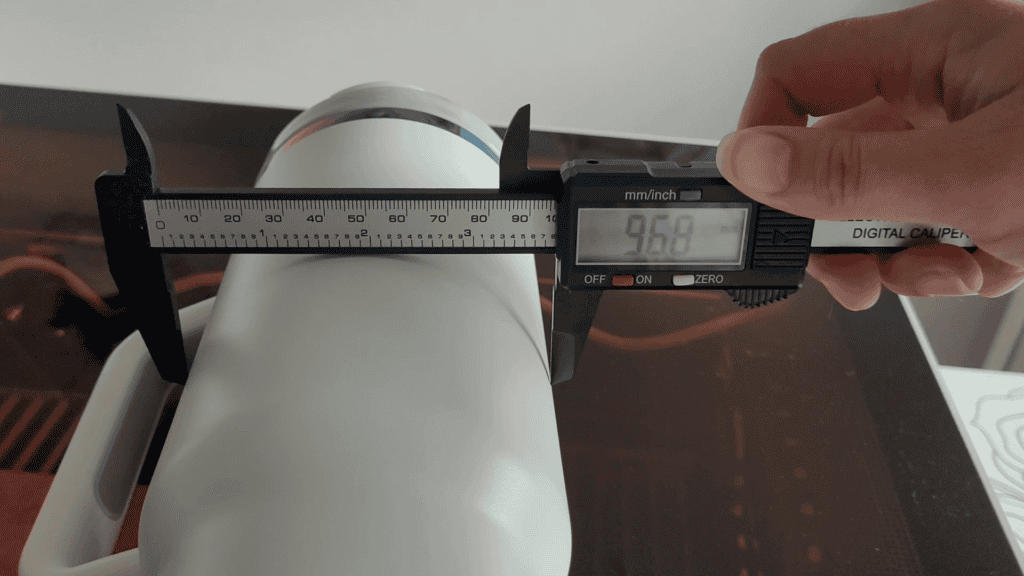 Measuring a white tumbler with digital calipers reading 96.8mm in diameter