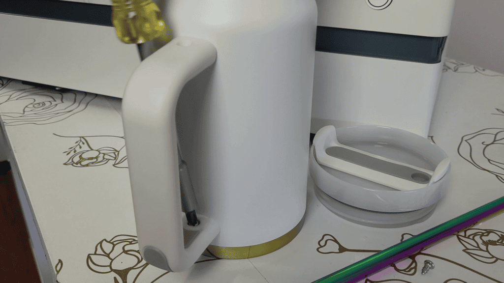 White 40oz tumbler and its lid on a craft table beside the WeCreat Vista laser engraver