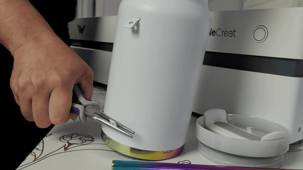 Using pliers to pull the rubber base ring off a white tumbler before engraving