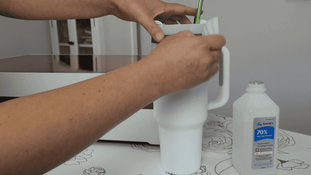 Wiping a white 40oz tumbler with 70 percent isopropyl alcohol to clean it before laser engraving