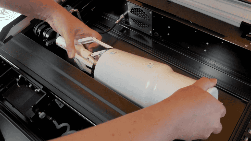 Loading a white 40oz tumbler onto the rotary attachment inside the WeCreat Vista