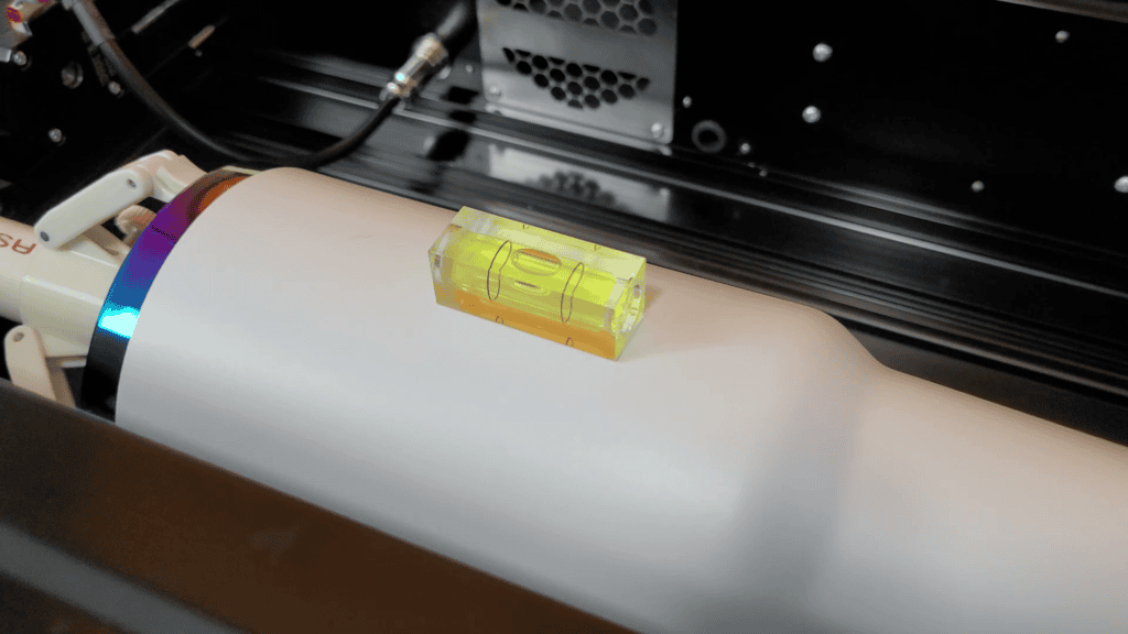 Bubble level resting on a white tumbler in the rotary to check the surface is level