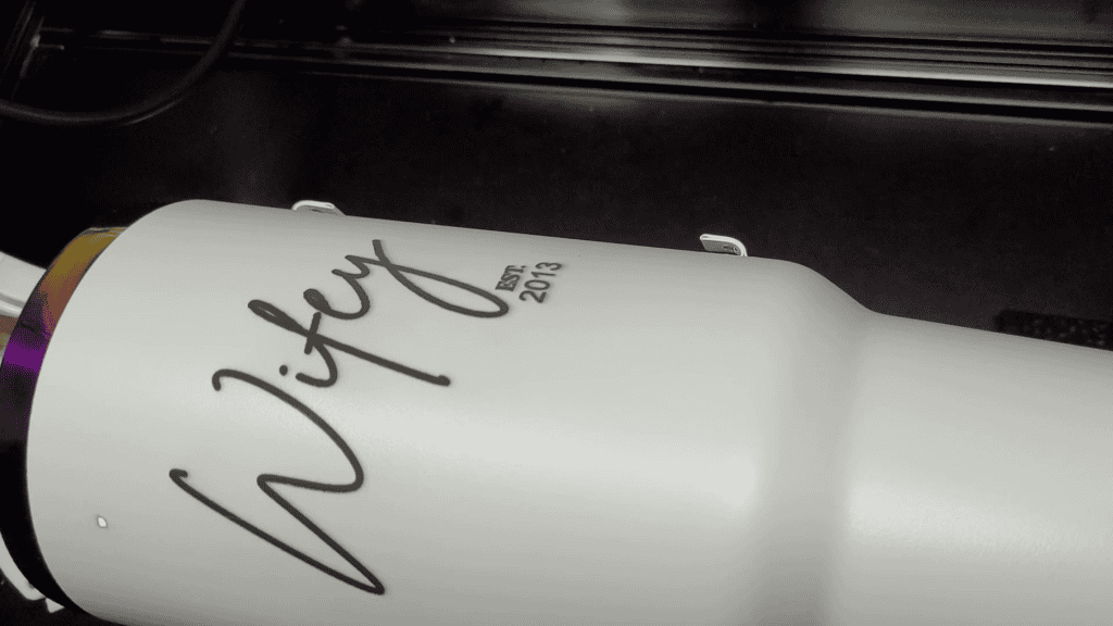 White tumbler turning on the rotary showing the finished Wifey engraving