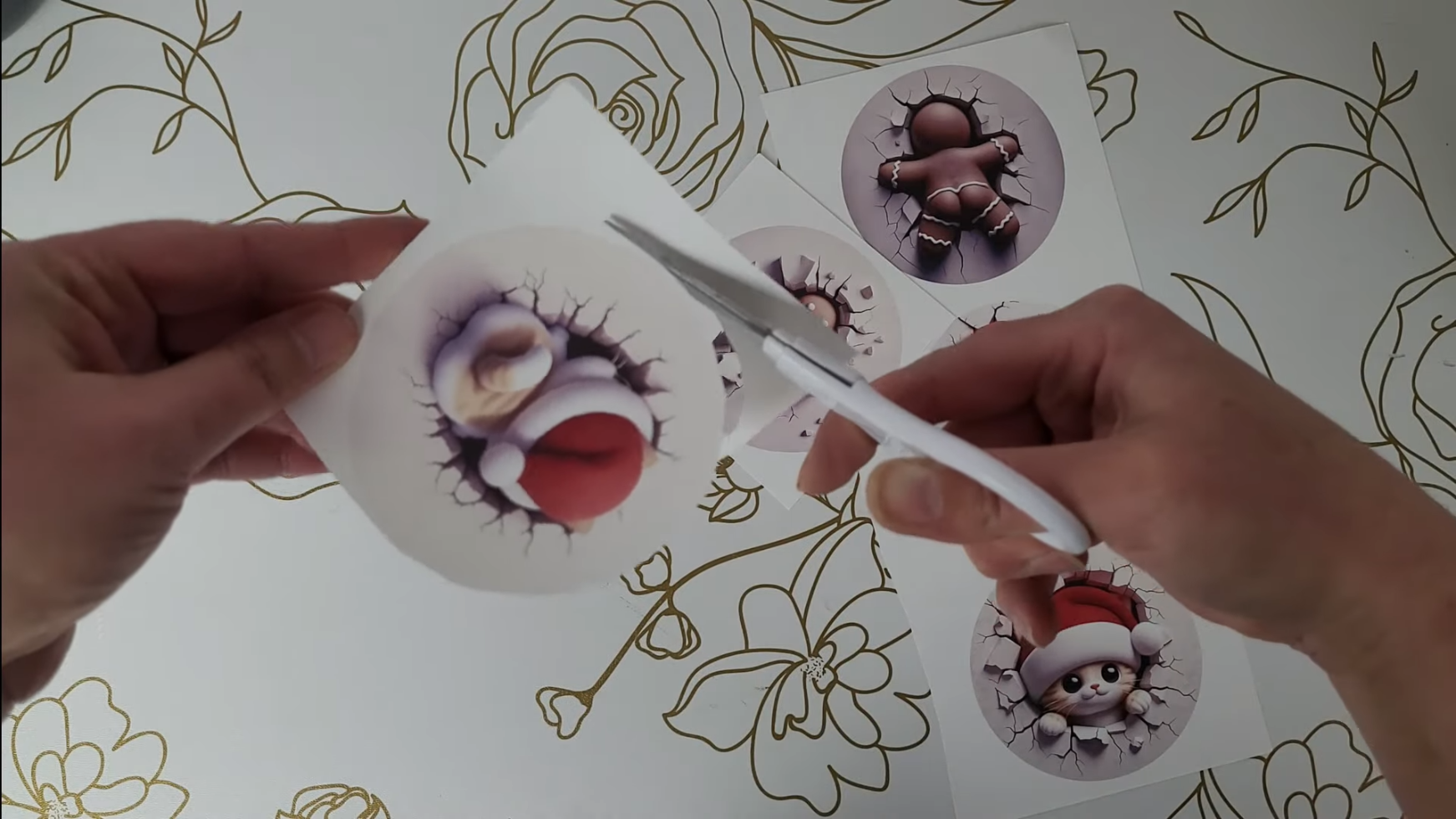 How to Make 3D Sublimation Ornaments That Pop Right Off the Surface 8 Kerri Adamczyk using scissors to cut out printed 3D sublimation ornament designs from sublimation paper - showing gingerbread, dinosaur, and cat Christmas designs ready for heat pressing