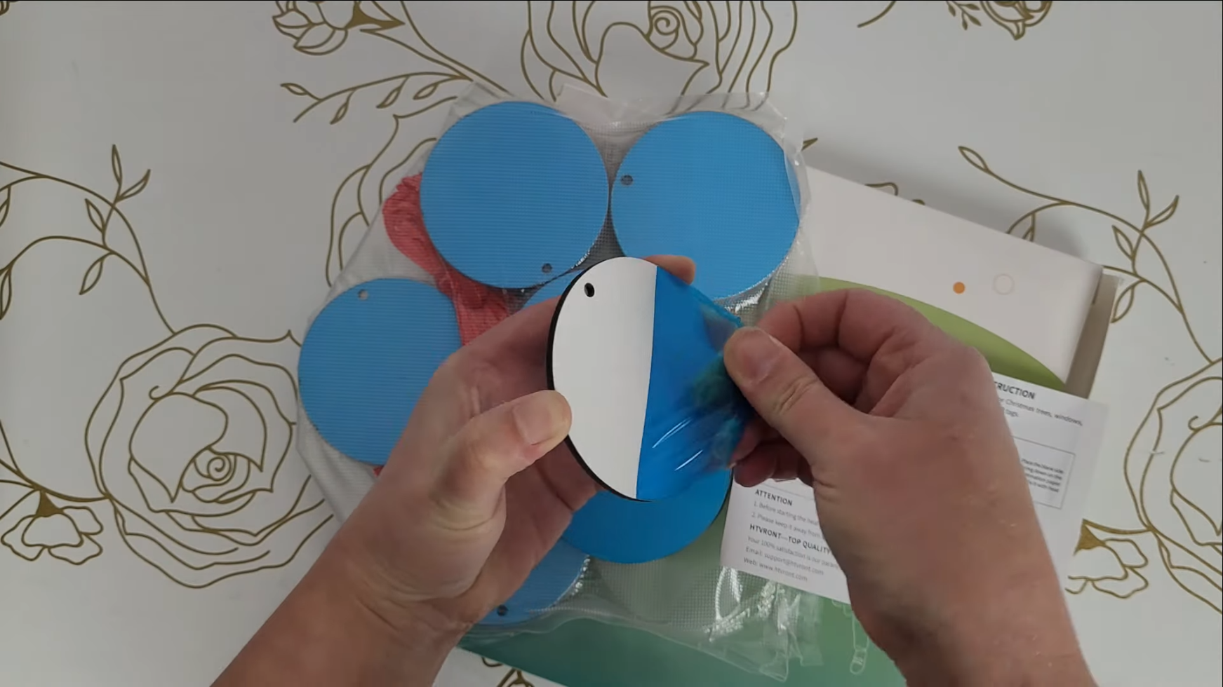 How to Make 3D Sublimation Ornaments That Pop Right Off the Surface 9 Kerri Adamczyk's Hands peeling blue protective film off a white sublimation ornament blank - the ornaments appear blue in packaging but are actually white underneath the protective coating