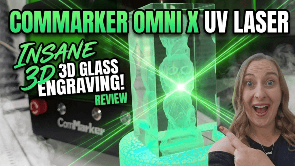 YouTube thumbnail featuring Kerri Adamczyk with an excited expression pointing at a 3D laser-engraved glass crystal block displaying an owl design. A ComMarker UV laser machine is visible on the left. Text overlay reads "ComMarker Omni X UV Laser" at the top, with "Insane 3D Glass Engraving! Review" on the left side. Green laser beam effects accent the image.