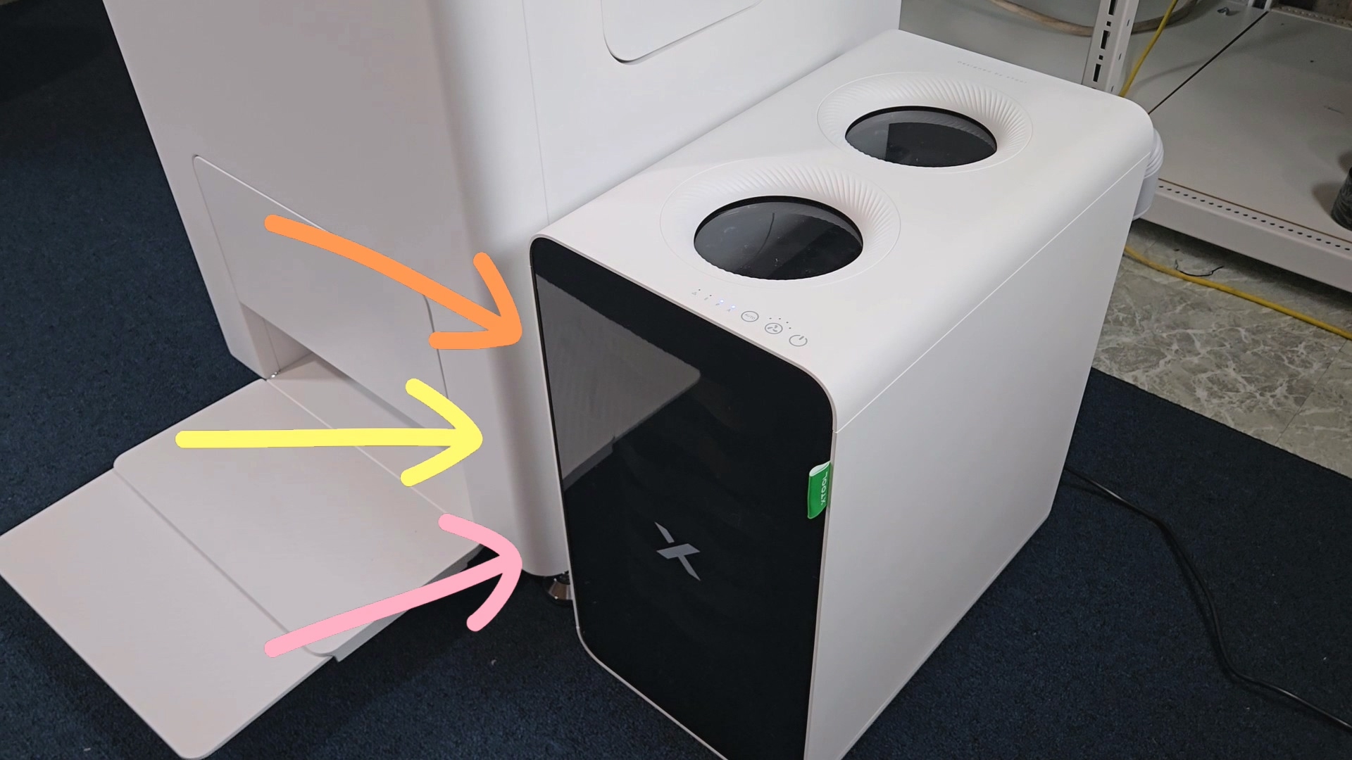 xTool SafetyPro AP2 Air Purifier next to xTool Apparel Printer with colored arrows pointing to filter access panel, showing dual circular vents on top of purifier