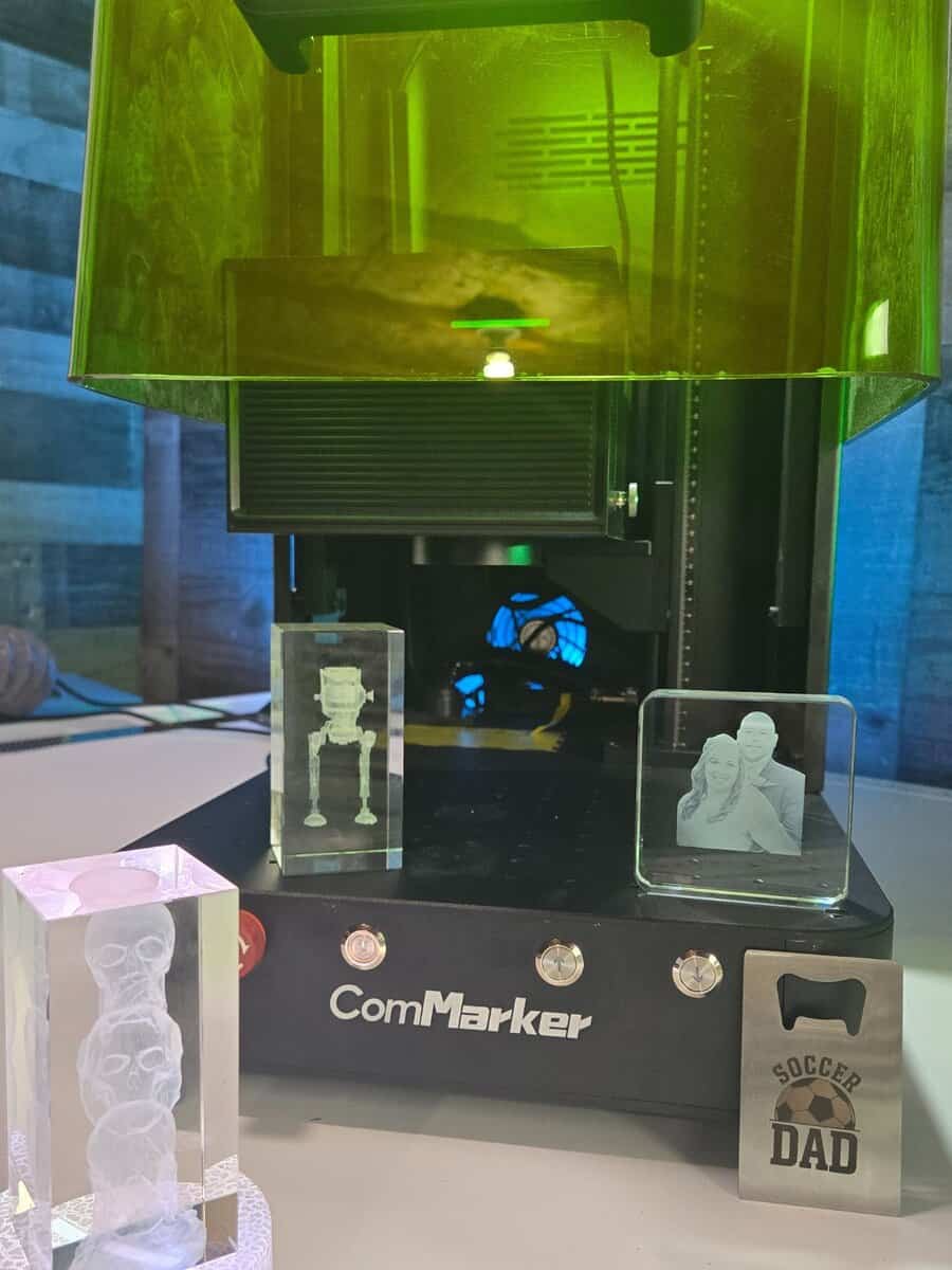 ComMarker Omni X UV laser engraver showing multiple 3D crystal and glass cube engraving projects