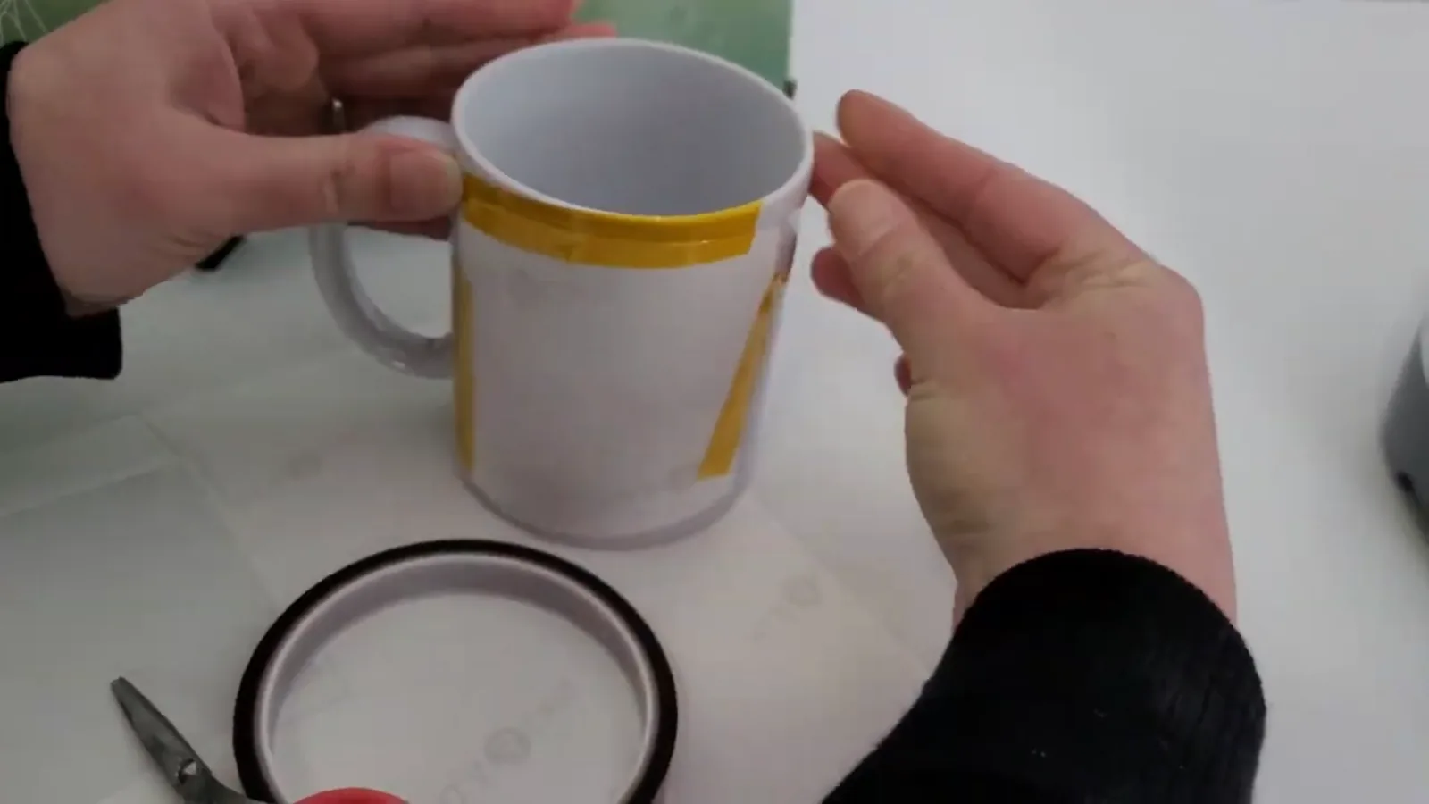 Sublimation design taped face down onto a blank mug with yellow thermal tape