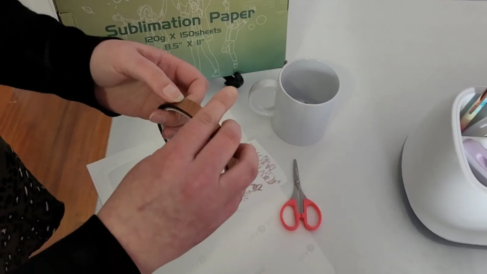 Supplies to sublimate a mug: blank ceramic mug, sublimation paper, thermal tape and scissors