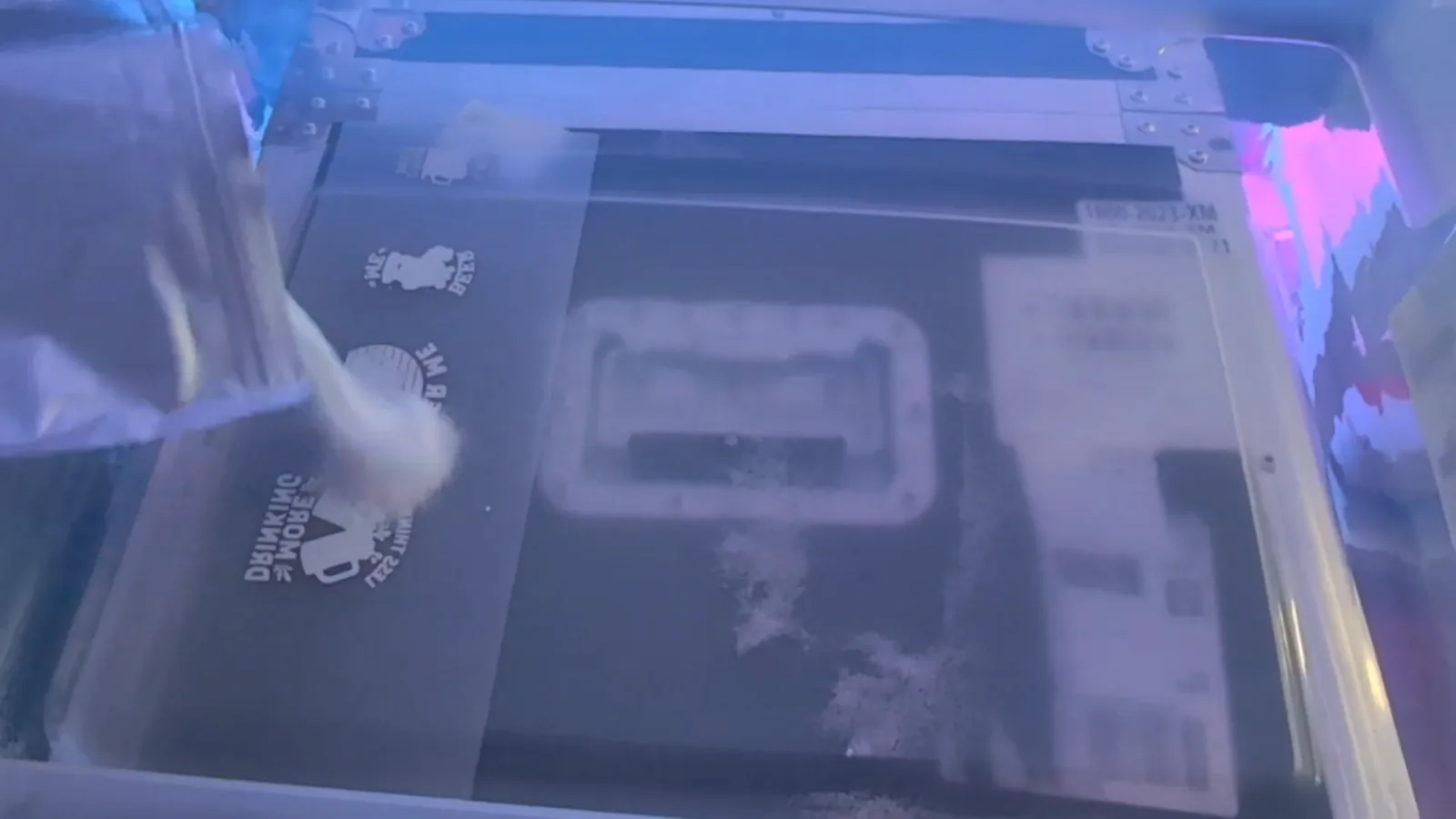 Hot melt adhesive powder being spread over the wet ink on a freshly printed DTF transfer