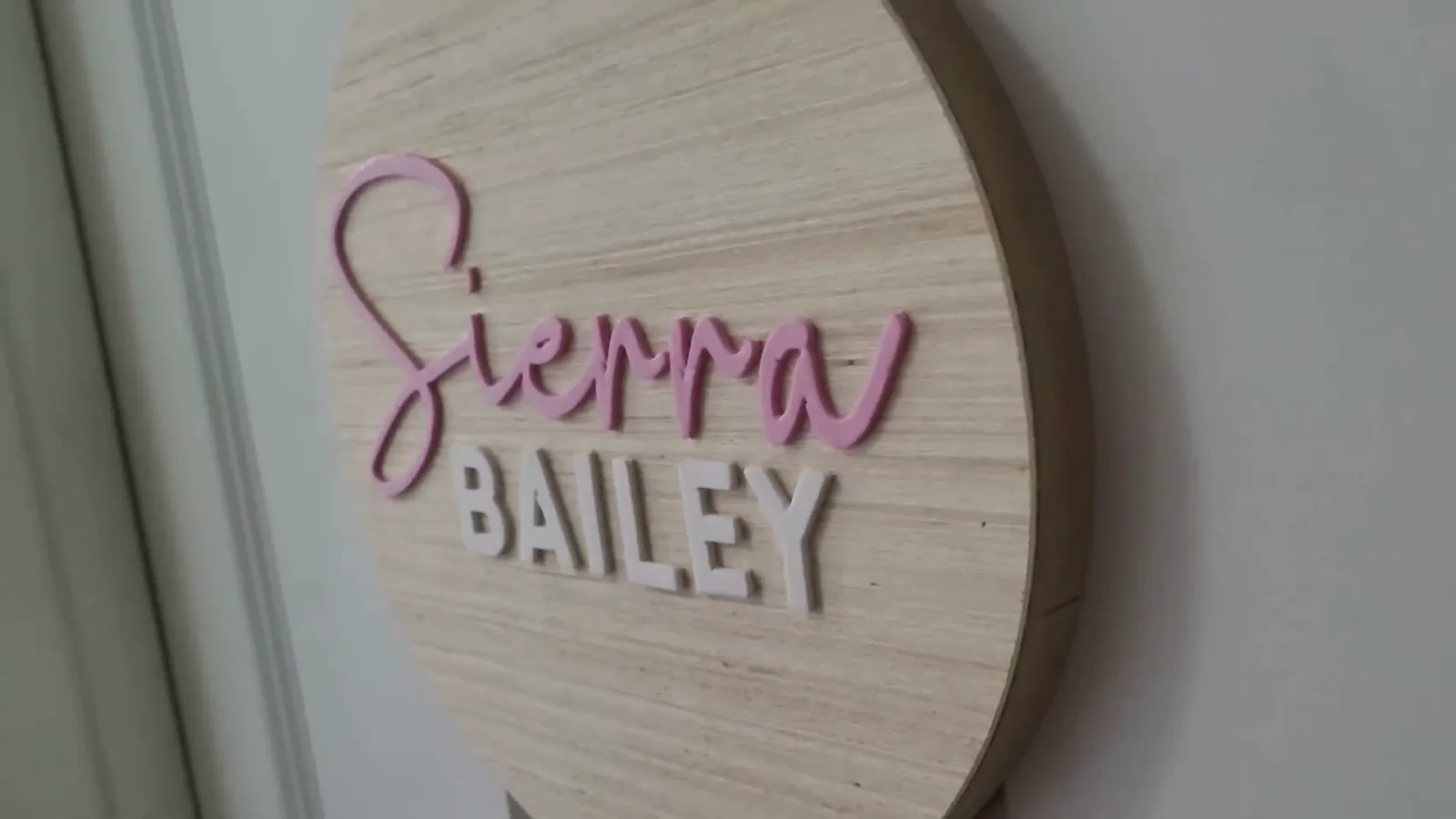 Wood round name sign with Sierra in the Ashley Southine script font and Bailey in the Avocado Family sans serif font