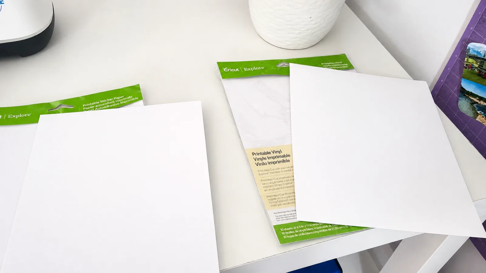 Cricut Printable Vinyl and Cricut Printable Sticker Paper packages opened side by side with sheets pulled out