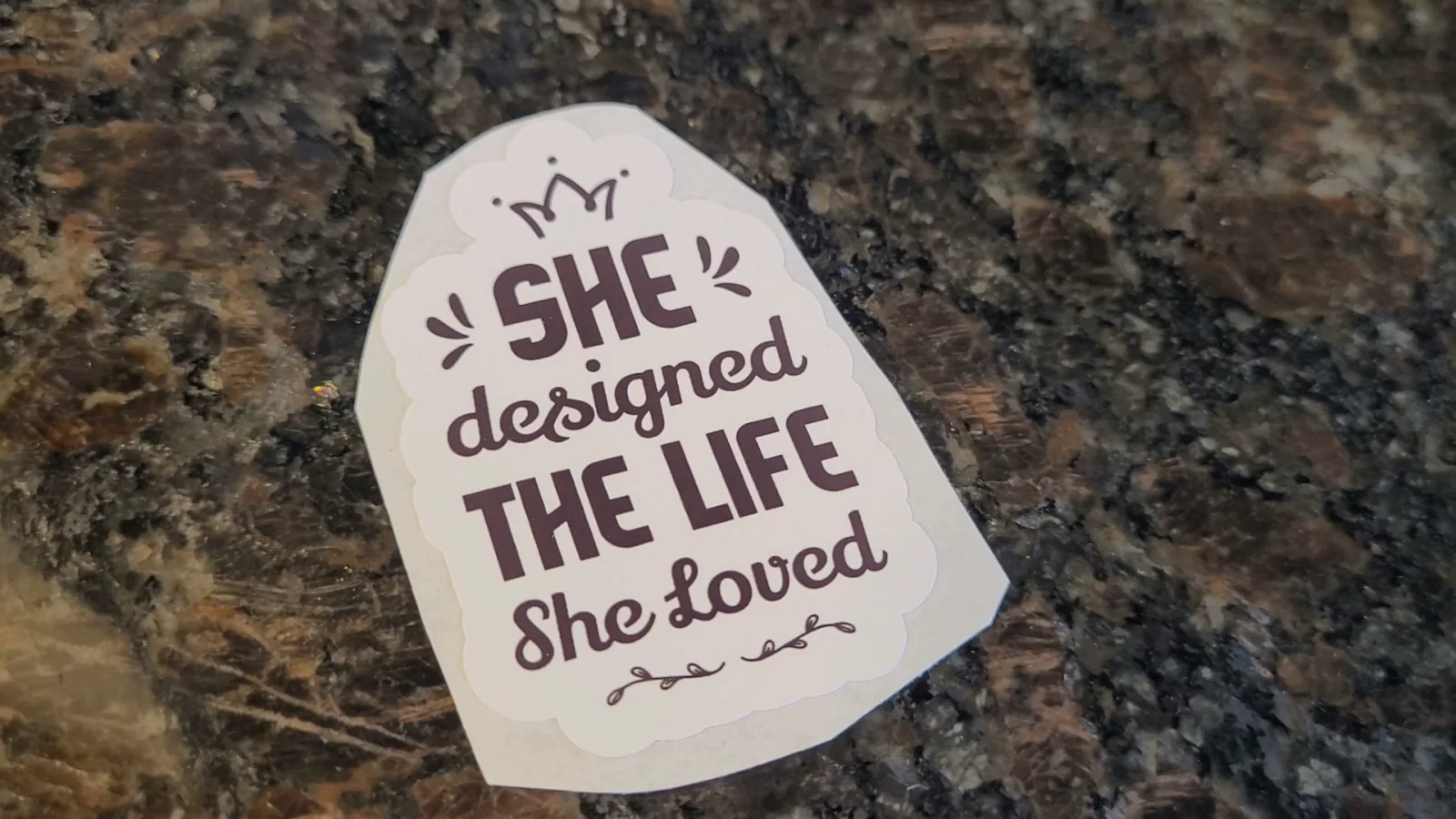 A finished die cut sticker reading She designed the life she loved, cut out as a single piece