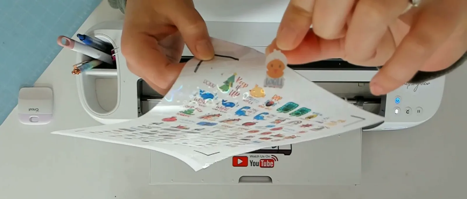 A single sticker being peeled off a kiss cut sheet while all the other stickers stay attached to the backing