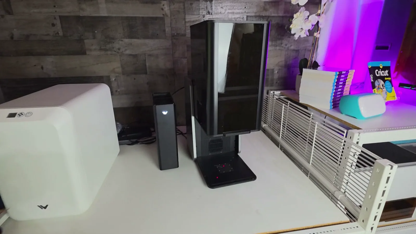 WeCreat Lumos Ultra enclosed desktop laser engraver set up on a craft room workbench next to its fume extractor