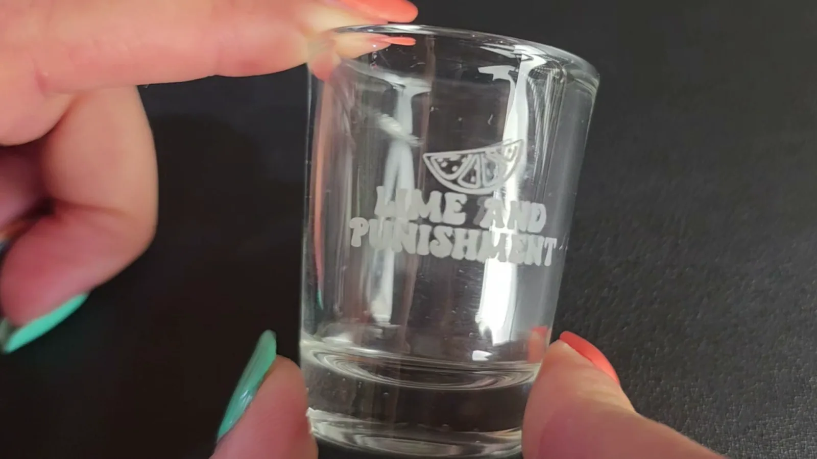 Clear shot glass engraved directly with a UV laser with no paint or coating, showing crisp white lettering