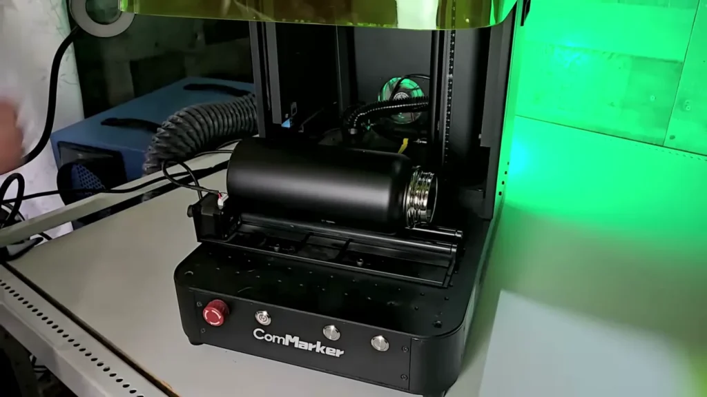 ComMarker Omni X UV laser with the R5 rotary roller and a black tumbler loaded for batch engraving