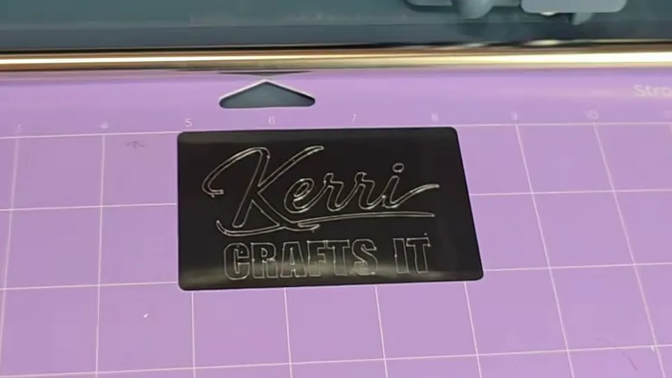 Black anodized aluminum business card engraved with the Kerri Crafts It logo on a Cricut StrongGrip mat