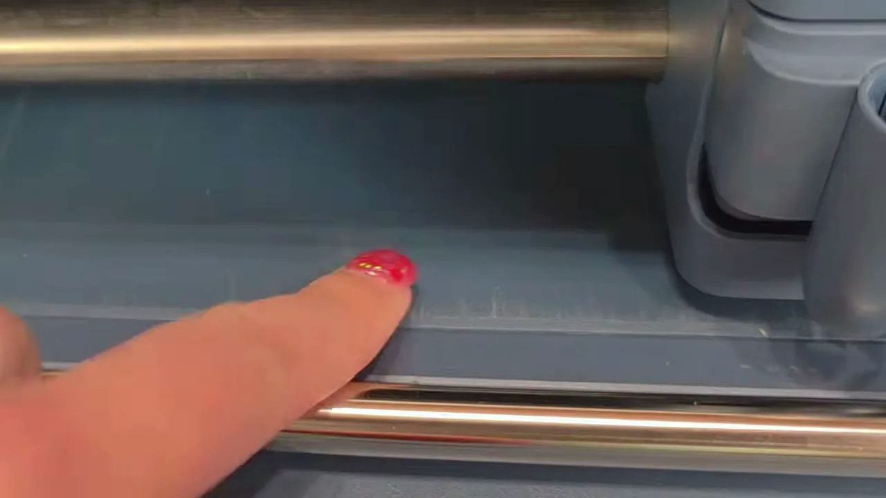 Finger pointing to scratched paint where the cutting mat feeds into a new Cricut Maker 5