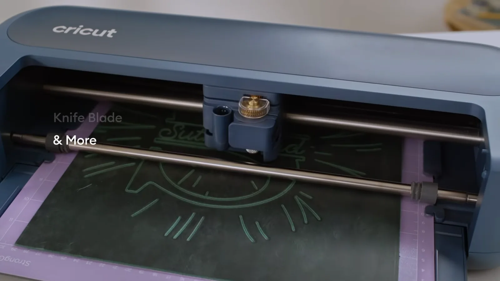 Close up of the single Cricut Maker 5 tool clamp holding a QuickSwap tool while engraving a dark material on a purple StrongGrip mat