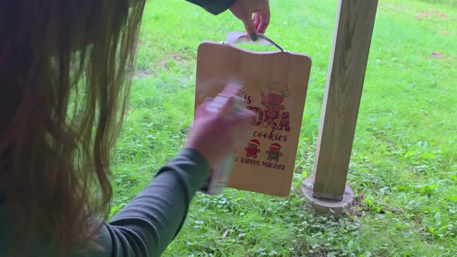 Spraying a printed wood cutting board with clear acrylic enamel spray outdoors to seal the xTool M2 print