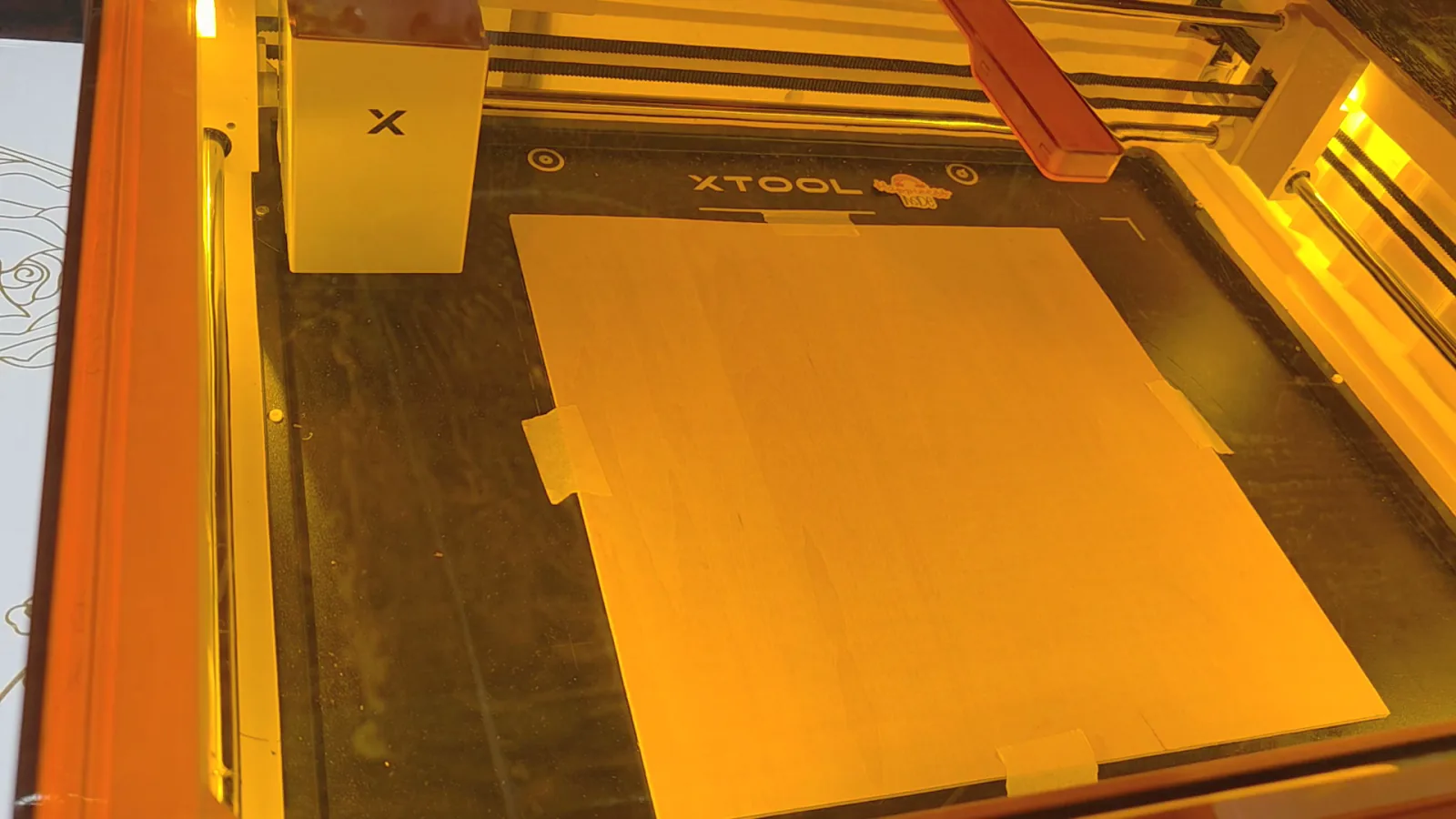 Sheet of 3mm basswood taped down inside the xTool M2 laser bed before printing